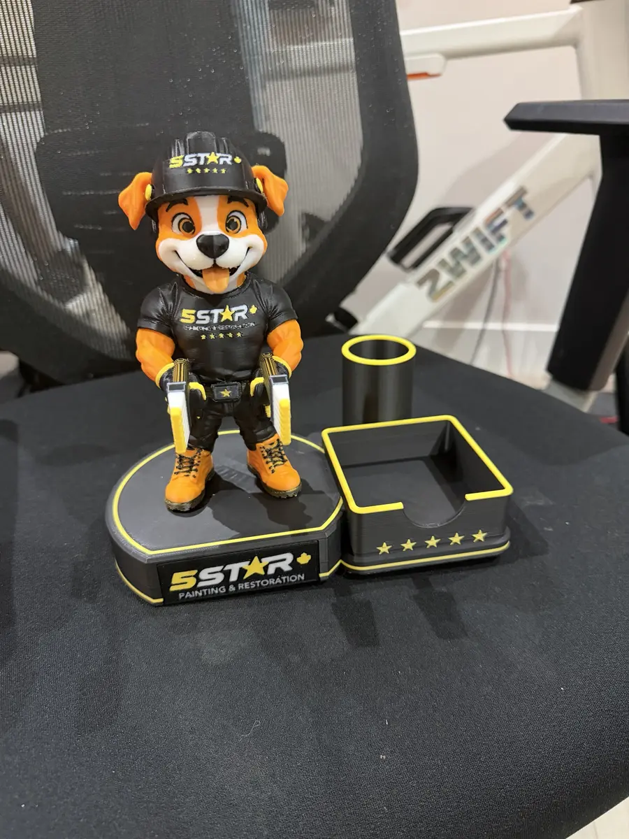 3D-printed orange and white dog mascot in a black 5 Star hard hat and t-shirt on a branded base with a pen cup and card tray
